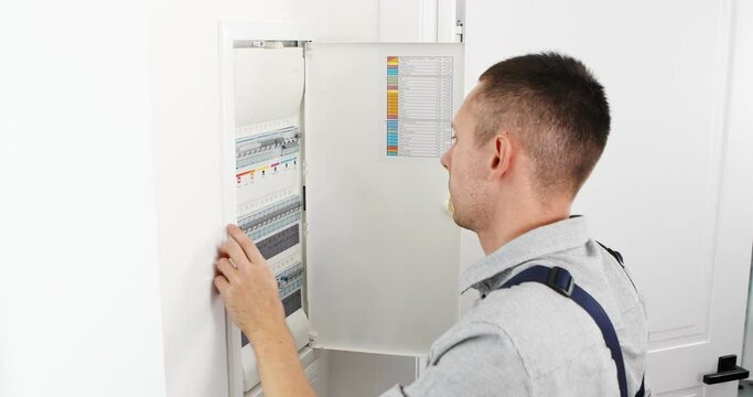 Hands of electrician with electric actuator equipment in fuse box