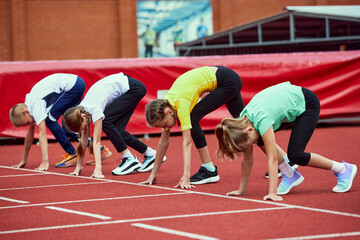 Start. Group of kids getting ready to run on treadmill at the stadium or arena. Little boys, girls in sportswear training as athletes outdoor. Concept of sport, achievements, studying, skills