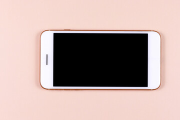 White phone smartphone with black screen lies on a pastel pink background
