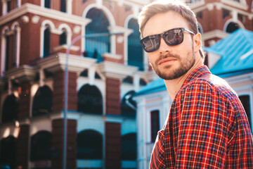 Portrait of handsome confident stylish hipster lambersexual model.Modern man dressed in shirt. Fashion male posing on the street background in sunglasses