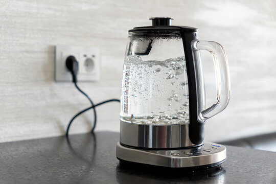 Transparent electric kettle with boiling water in the kitchen