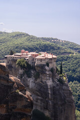 Fototapeta na wymiar Vertical shot of Holy Monastery Varlaam situated at top of a rocky precipice that is 373 meters above Pineios valley floor. Meteora, Greece