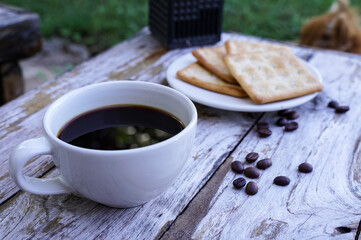 The hot black coffee in a white cup and the crackers are intense and go well together.