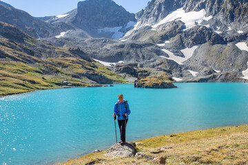 Fototapeta na wymiar The girl rises uphill against the background of a blue turquoise lake. Mountain landscape. A place for a healthy lifestyle. Caucasus, Russia