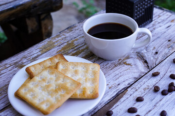 The hot black coffee in a white cup and the crackers are intense and go well together.