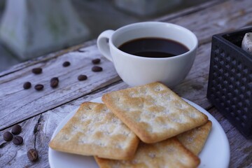 The hot black coffee in a white cup and the crackers are intense and go well together.