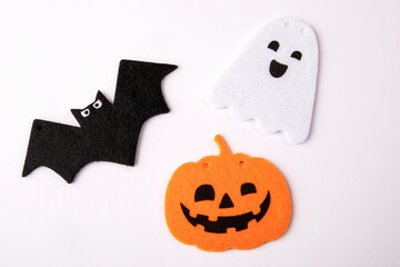 Halloween holiday decorations. orange pumpkin, bat and ghost in the hands of a man on a white background