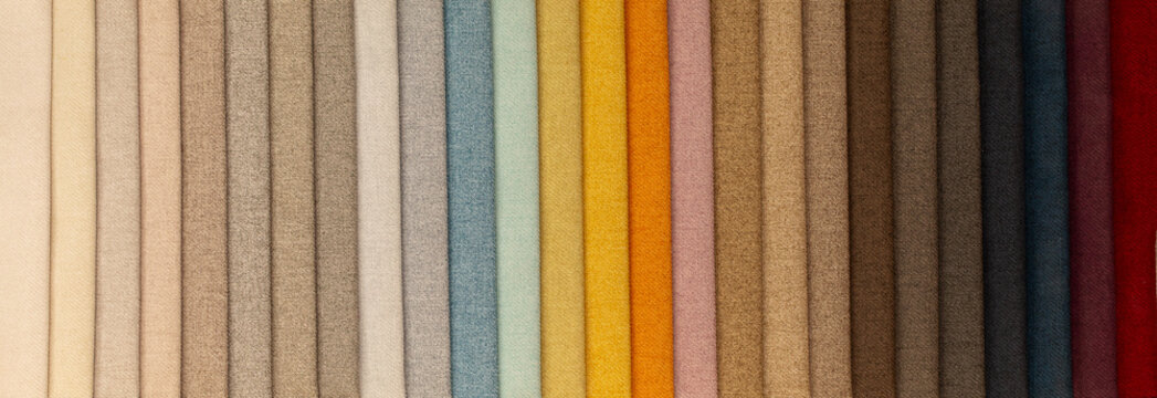 Fabric texture close up. Fabric swatches in different colors are stacked for selection. A variety of shades of upholstery material for furniture and interior. A set of multi-colored rolls of material. © Vera