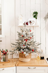 Fototapeta na wymiar Christmas tree in a white kitchen in a bright interior