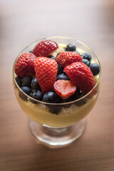 Pudding dessert with fresh strawberries and blueberries in a glass bowl