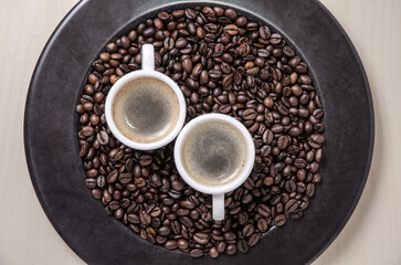 Coffee espresso beans on dark background plate and cups with crema, close-up, flat lay background...