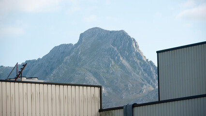 Monte rocoso tras techos de naves industriales