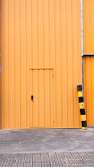 Puerta metálica naranja en nave industrial de hormigón 