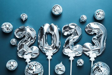 Happy New Year 2023. silver foil balloons and disco balls on blue background. Festive concept. Flat lay, top view,