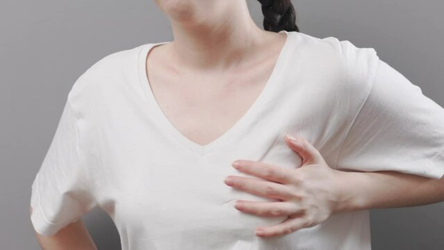 Adult woman grabs her chest with hands, experiencing severe pain. Lung and heart disease. Close up. The concept of a heart attack and infarction.