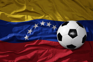 Naklejka premium vintage football ball on the waveing national flag of venezuela background. 3D illustration