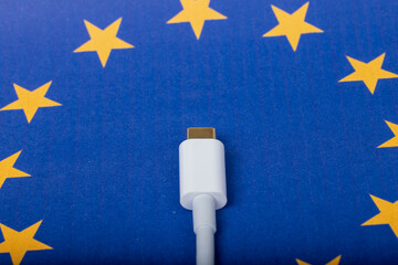 Concept for EU law to force USB-C chargers for all phones. EUROPEAN UNION flag and USBC universal charging cable as a standard for small electronic devices