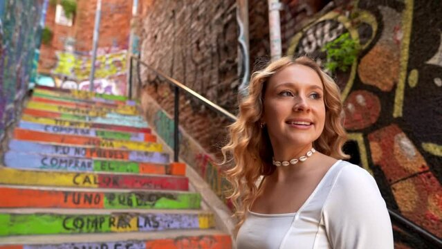 Beautiful blonde girl looking back on colorful stairs with Pablo Neruda's poem, Valparaiso, Chile - Slow motion