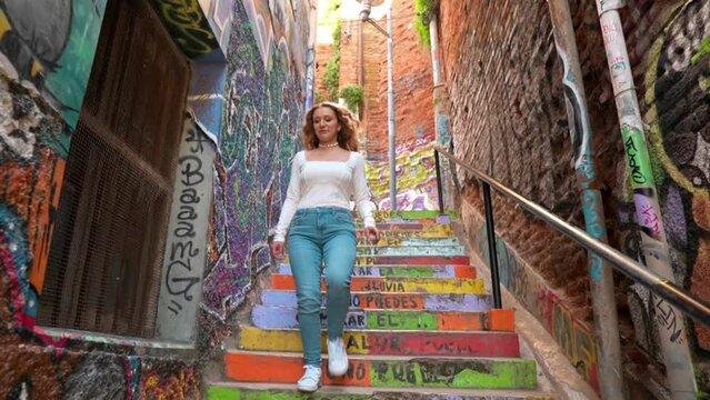 European blonde female running down the colorful stairs of cerro alegre narrow street in Valparaiso, Chile - Slow motion