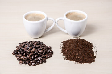 Two coffee cups or mugs with beans and ground coffee on wooden desk or table, I like, love coffee, close-up, coffee making concept