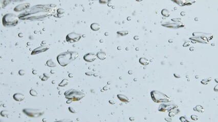 Air bubbles rising water surface closeup. Bubbling mineral liquid in light