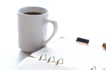コーヒーを飲みながらリング式のシステム手帳でスケジュール調整