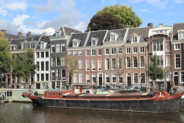 Obraz premium Amsterdam Amstel River View with Traditional Buildings and Boat, Netherlands