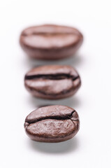 Vertical row of coffee beans order aligned, organization concept, close-up macro still life on white background