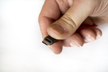 Hand holding a usb-c type cabel on a whith background, selective focus, macro, close-up