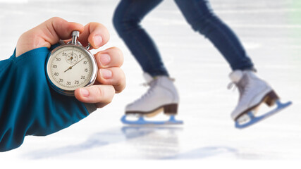 measuring speed on skates with a stopwatch. hand with a stopwatch on the background of the legs of...