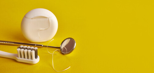 Dental mirror, dental floss and toothbrush on a yellow background. Dental care.