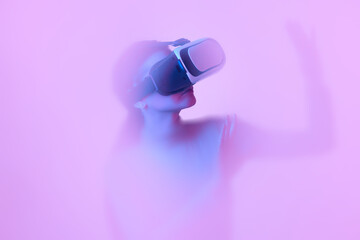 Female model in VR goggles immersed in clouds of smoke, fog on a pink neon background with a backlight diffuser.