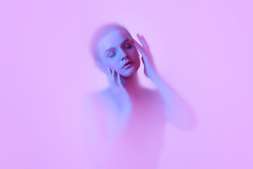 Mystical portrait of young tender girl immersed in clouds of smoke, fog on pink neon background...