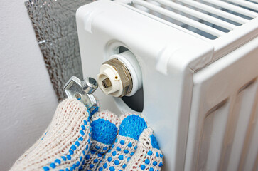 Radiator bleed key in plumber's hand. Adjust heating system, preparing the house for the new cold autumn or winter season.