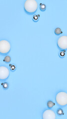White and silver Christmas balls on pastel blue background with copy space. Flat lay