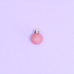 Pastel pink Christmas ornament on pastel purple background. FLat lay