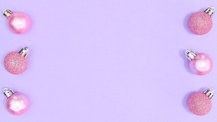 Pastel pink Christmas ornaments on left and right side of pastel purple background with copy space. FLat lay