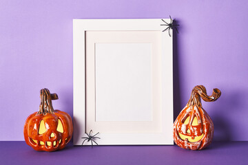 Halloween composition with ceramic pumpkins jack lantern and frame on table wall background. Greeting card template