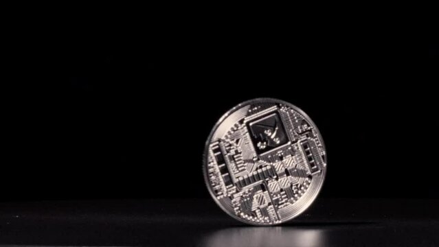 Silver bitcoin spinning in slow motion against black background until it leaves the screen