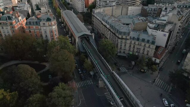 Metro train passing on Cambronne bridge in Paris town center. Aerial top down backward