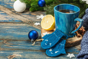 Hot drink with crocheted funny mittens. Traditional winter decor, fir tree branches, snowflakes