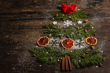 Creative fir tree from evergreen branches, dried lemon slices and snowflakes
