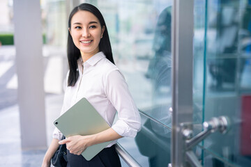 Asian businesswoman holding a tablet looking away smart business concept, smart woman .