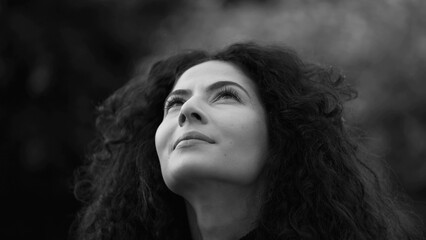 Woman standing outdoors in contemplation in monochromatic. Black and white artistic clip of 30s female person staring up at SKY