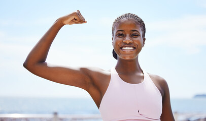Fitness, portrait and black woman flexing muscle at the beach in summer after strength training, exercise and workout. Smile, motivation and happy girl outdoors with healthy and strong arm biceps - obrazy, fototapety, plakaty