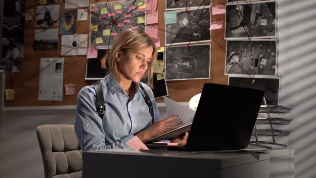 Detective processing evidence in office, working at desk in her office, young serious FBI agent in uniform