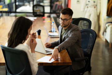 Businessman gives businesswoman dismissal contract to sign.