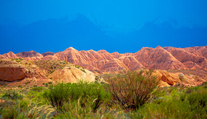 Natural unusual landscape of red rocks against the backdrop of blue mountains. The extraordinary beauty of nature is similar to the Martian landscape. Amazingly beautiful landscape.