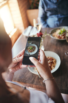 Phone, food and social media with the hands of a woman taking a photograph while eating in a restaurant during a date. Mobile, internet and romance with a female snapping a picture while dating