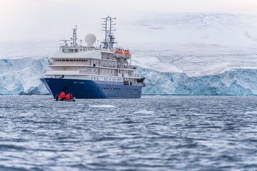 blaues Expeditionsschiff vor antarktischer Eisberg Landschaft in der Cierva Cove - ein tiefer...